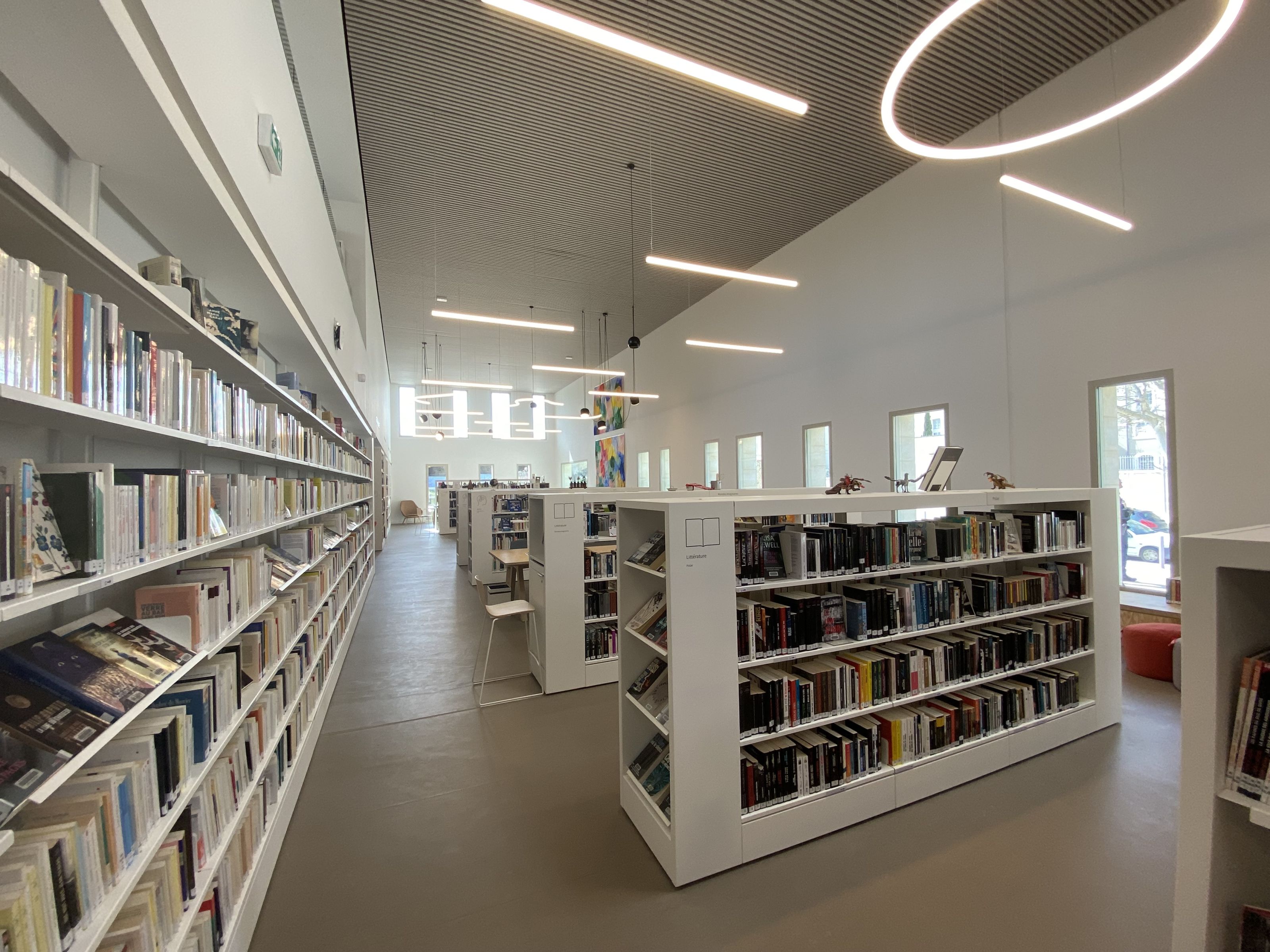 Intérieur de la médiathèque de Tarascon. Rayonnages blancs plein de livres.