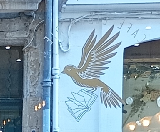 Logo de la librairie Le Chant du monde à Aix-en-Provence : un livre emporté par un oiseau.