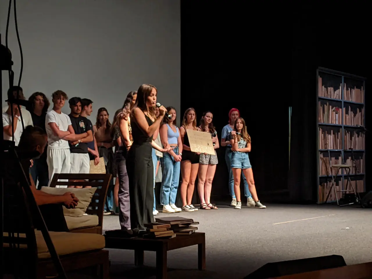 Des adolescents sont sur scène. Une jeune fille tient un micro.