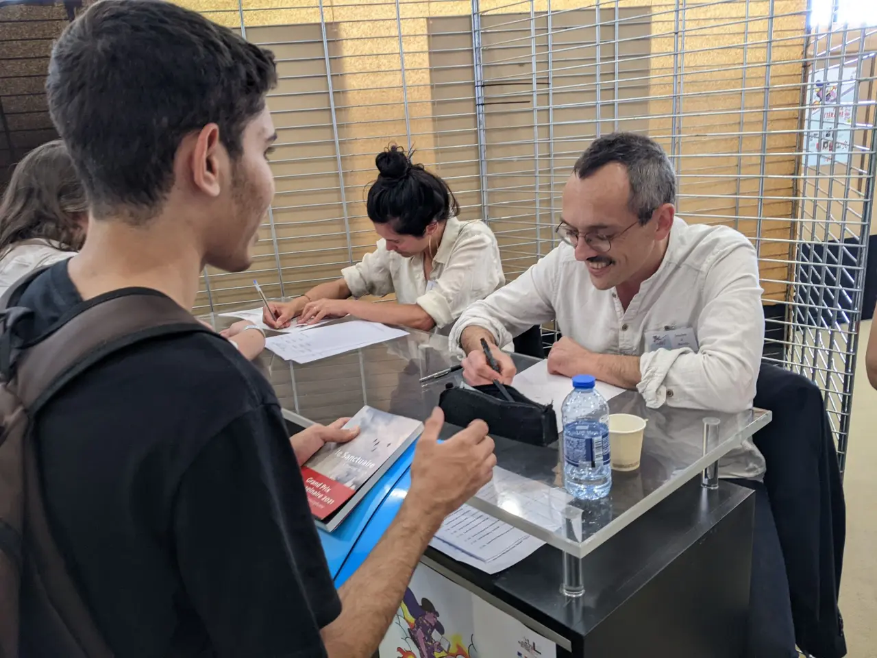 Deux auteurs signent des dédicaces à des jeunes.